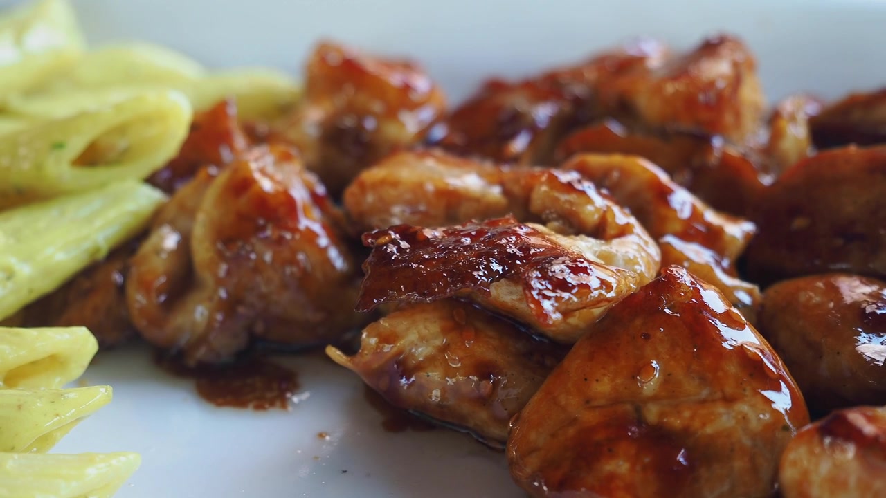 Pezzi di pollo glassati serviti con penne