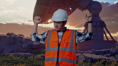 asian male engineer with safety helmet screaming goal and dancing celebrating with large satellite dish
