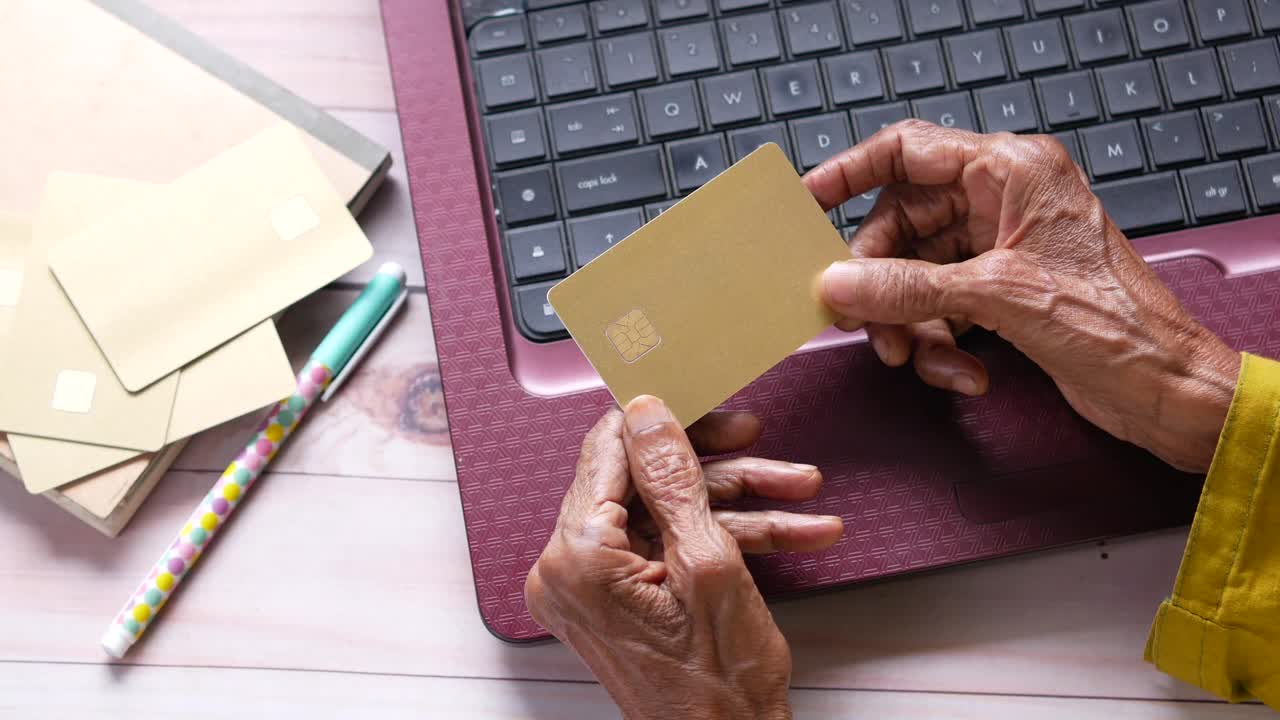 persona mayor que utiliza una computadora portátil y una tarjeta de crédito