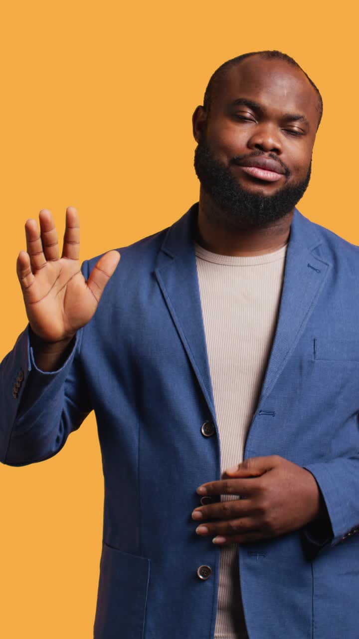 Vertical video Man reluctantly doing salutation hand gesture, saying goodbye, studio background
