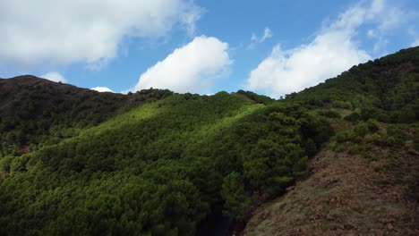 Green-vibrant-mountains-and-blue-sky-in-Spain,-aerial-drone-ascend-view