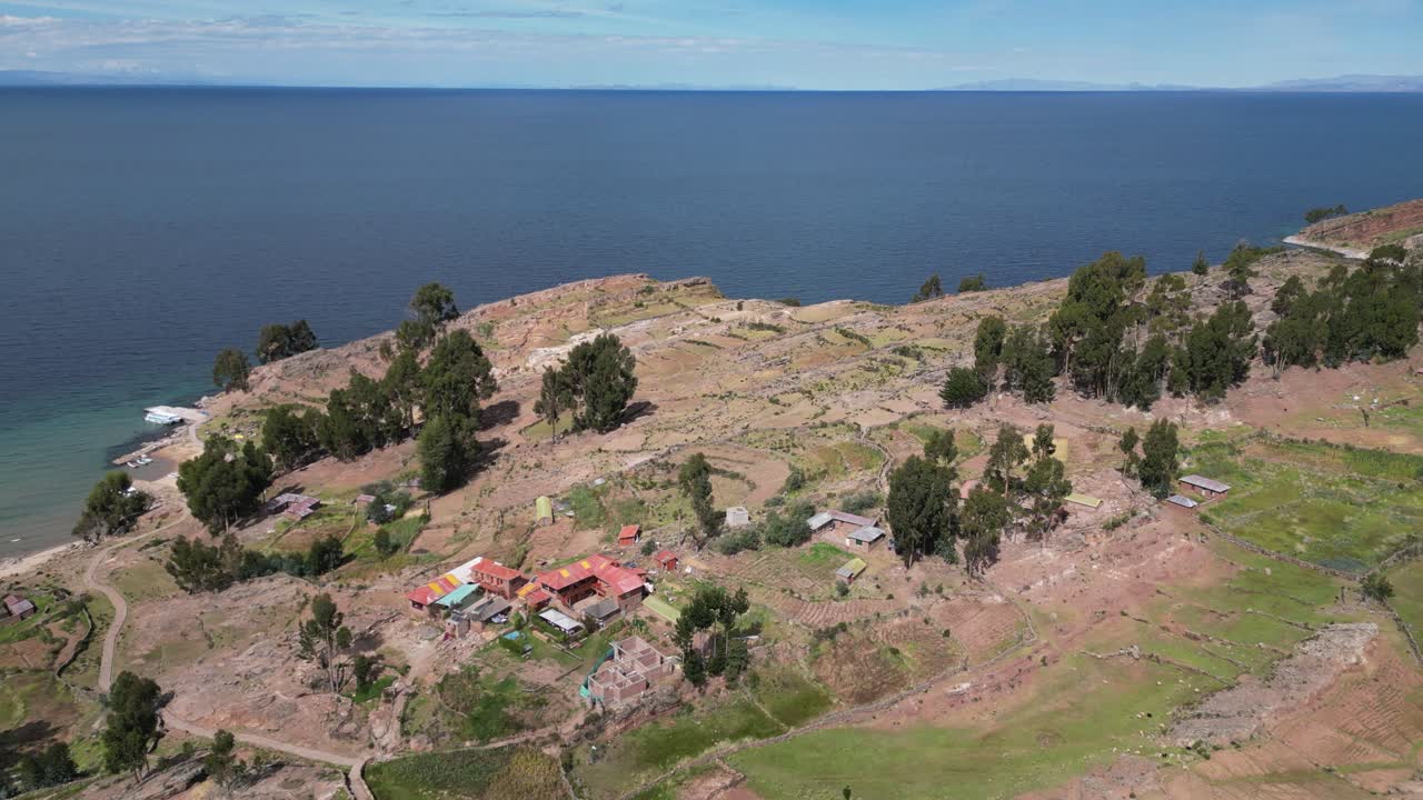 Aerial descends to farmhouse terraces on shore or Lake Titicaca, Peru