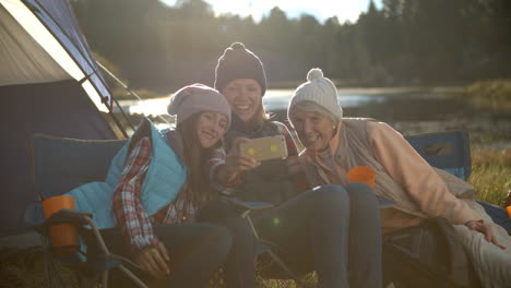 mother, daughter and grandmother taking selfie outside tent