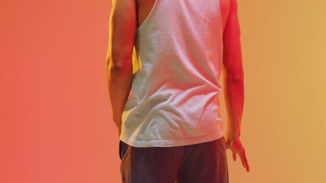 video de la vista trasera de un jugador de baloncesto masculino biracial rebotando la pelota sobre un fondo naranja a amarillo