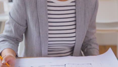 female architect in office at desk working on plans for new building