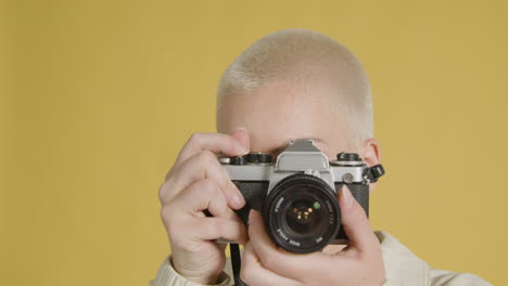 Woman-looks-into-lens-and-takes-photograph-on-vintage-camera