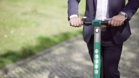 Cropped-shot-of-businessman-riding-scooter-outdoor