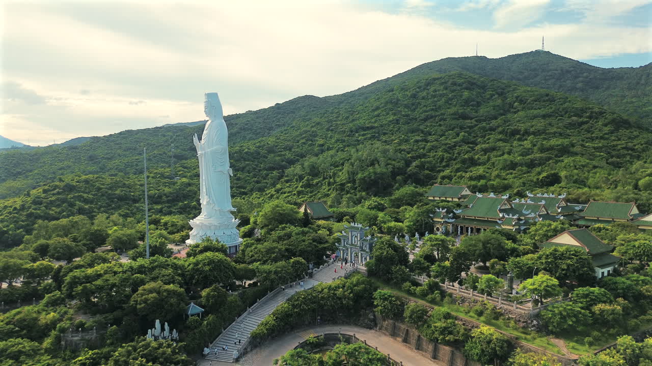 Góc chụp từ trên cao bằng thiết bị bay cho thấy tượng Phật Bà trắng khổng lồ (Quán Thế Âm Bồ Tát) đứng giữa những ngọn núi xanh tươi tại quần thể Chùa Linh Ứng ở Đà Nẵng