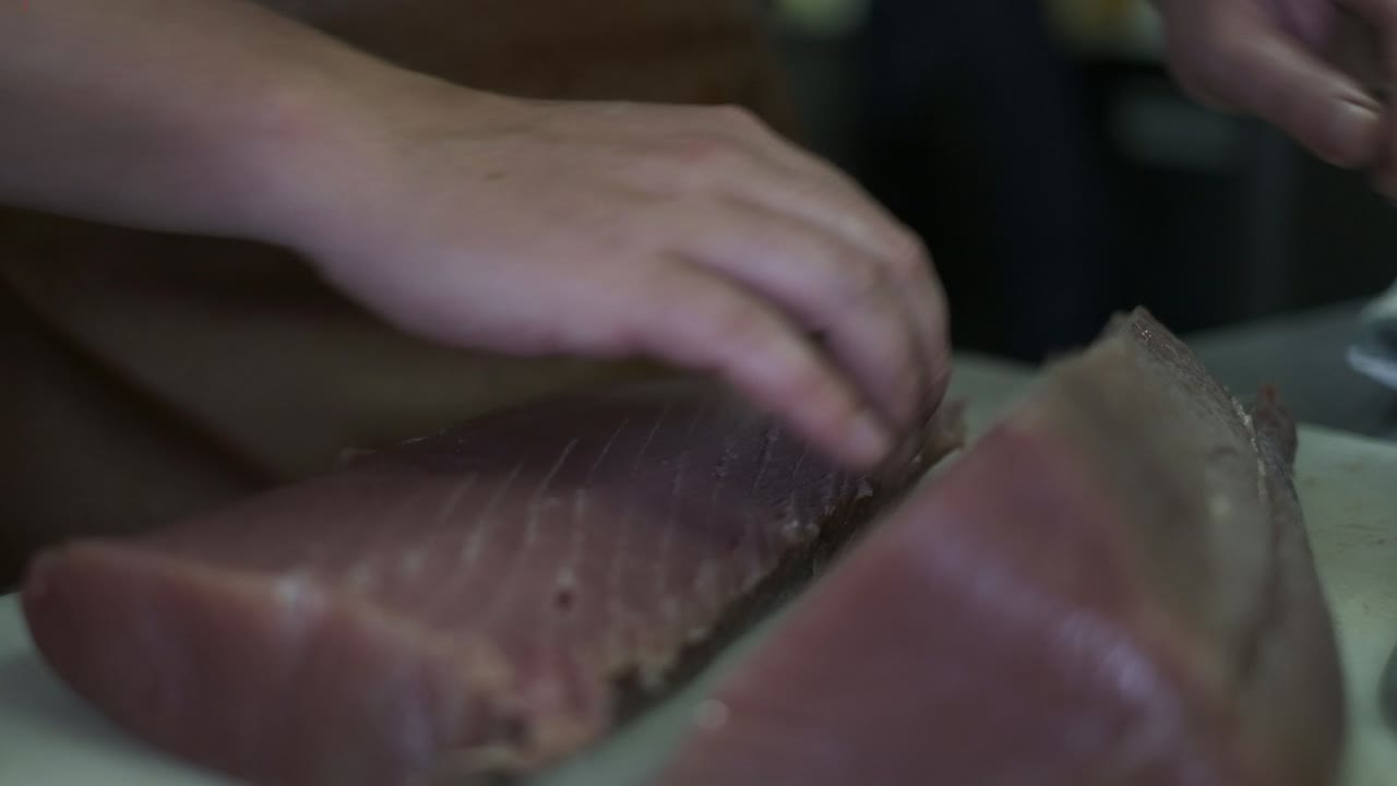 chef o cocinero cortando carne o pescado en la cocina con un cuchillo de carnicero