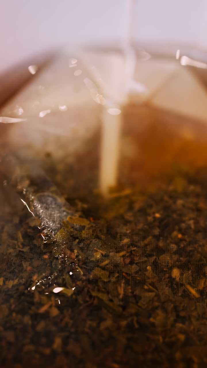 Close up of a tea bag brewing into a red cup. Vertical