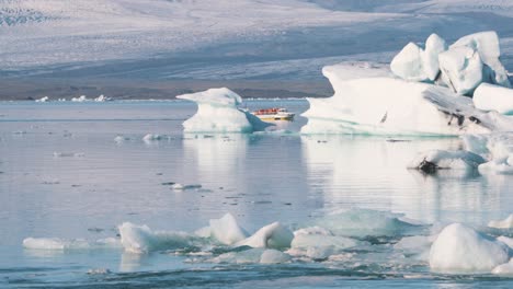 cruise boat with tourists sailing in arctic sea with icebergs, iceland