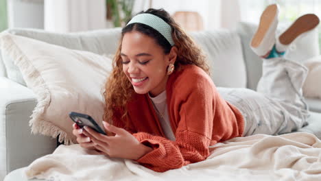 young woman relaxing on a couch and using a smartphone