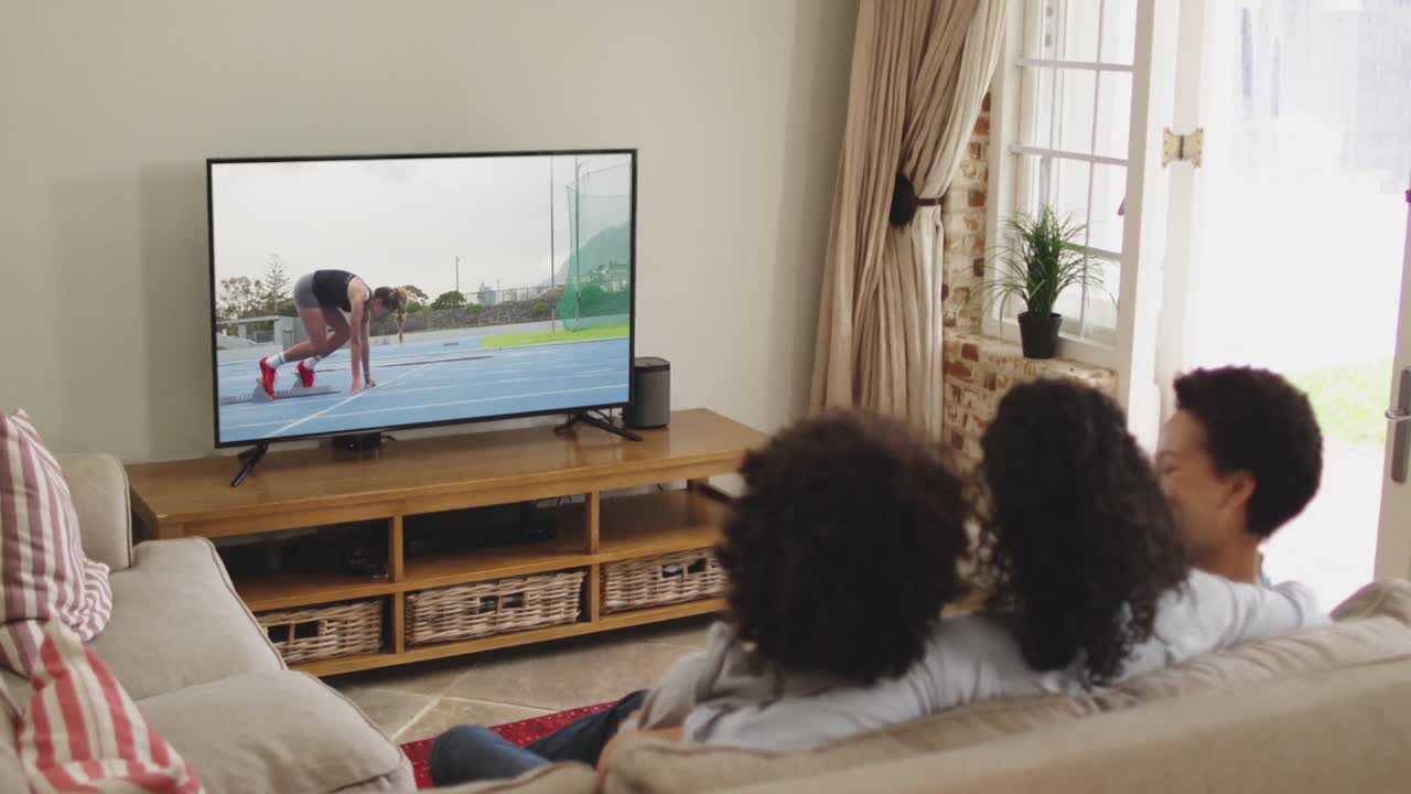 Famiglia felice seduta a casa insieme che guarda la corsa di atletica in TV
