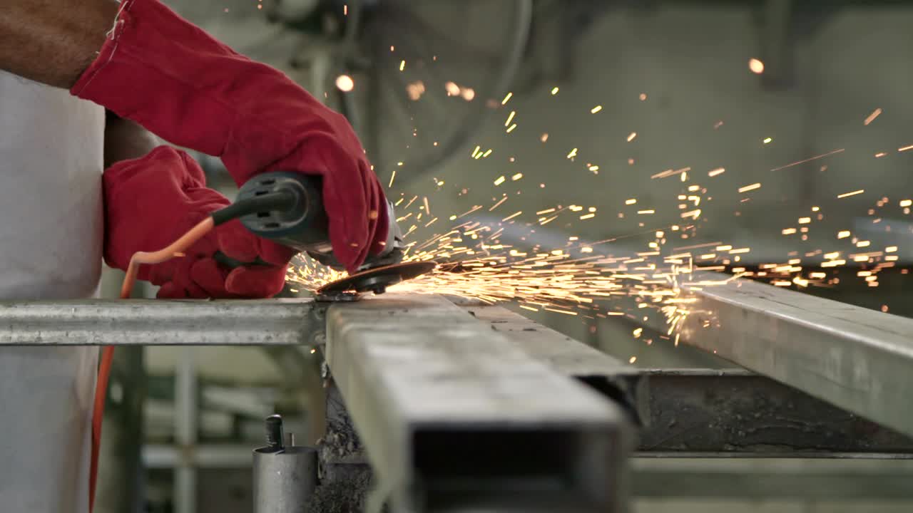 movimiento lento de un trabajador usando un molinillo de metal con chispas volando en una tienda de metal