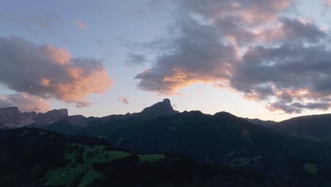 puesta de sol cinematográfica vista aérea inclinada hacia abajo del sass de putia en las dolomitas besadas por nubes