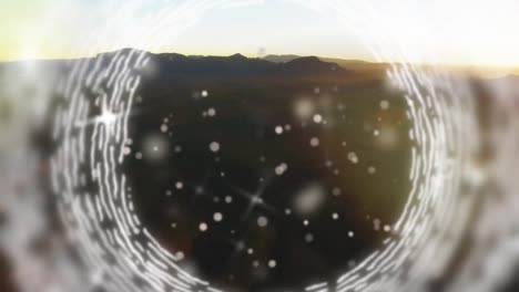 Animation-of-white-glittering-specks-and-circles-spinning-over-landscape