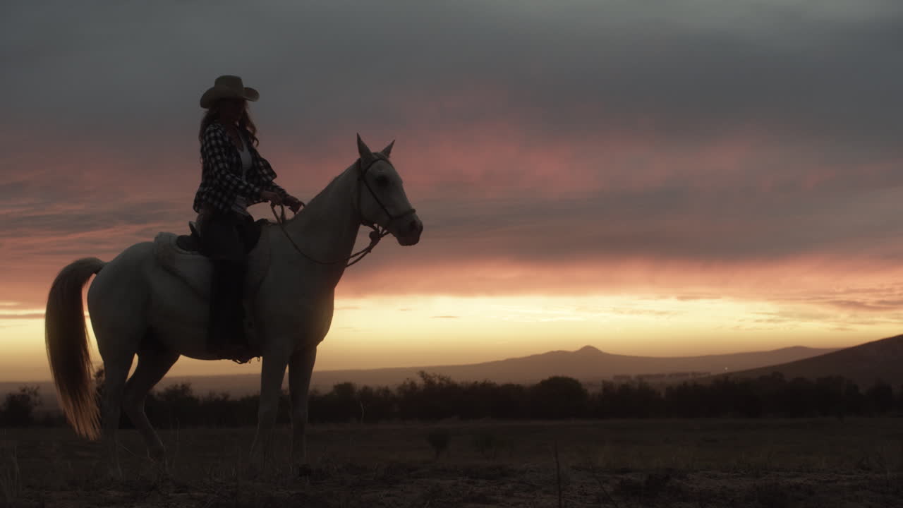 una mujer joven montando un caballo en un rancho al atardecer
