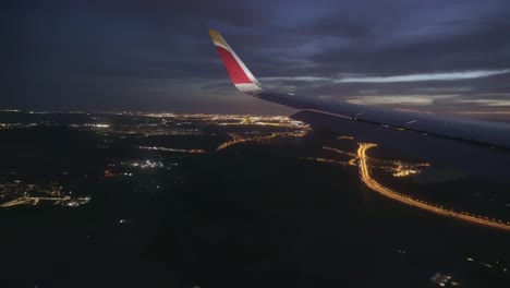 aerial view of madrid city lights during night view from a plane window plane wing visible during blue hour