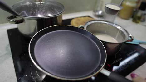 The-process-of-cooking-homemade-pancakes.-Woman-pours-pancake-dough-on-pan