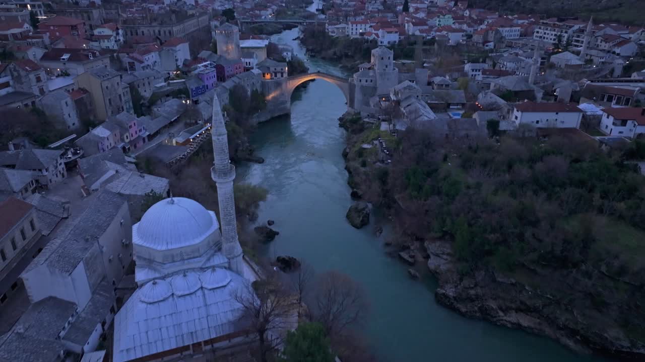 Renkli bir alacakaranlık gökyüzünün altında dimdik duran Stari Most'un havadan görünümü