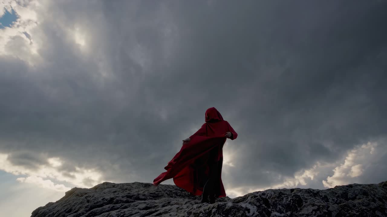 Woman in Red Cape on Mountain Top During Storm