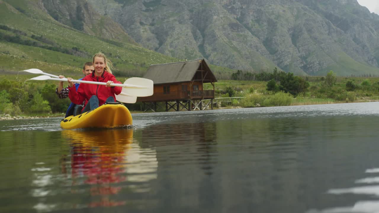 Coppia caucasica che si diverte durante un viaggio in montagna, facendo kayak insieme su un lago