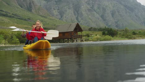 caucasian couple having a good time on a trip to the mountains, kayaking together on a lake