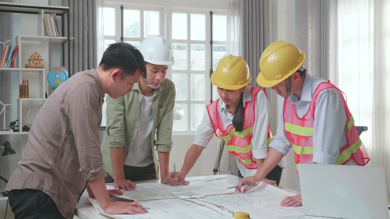 Three Asian Engineers With Helmets Presenting Work On The Tablet To A Man At The Office