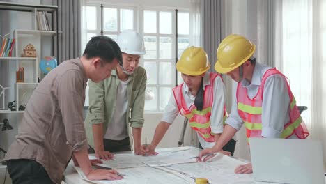 three asian engineers with helmets presenting work on the tablet to a man at the office
