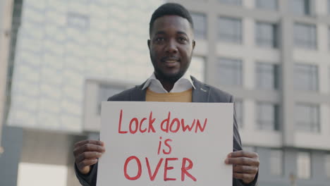 man holding sign saying 'lock down is over'