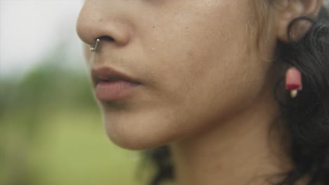 a rack focus close up shot of the face of a young attractive asian female outdoors in a field, india