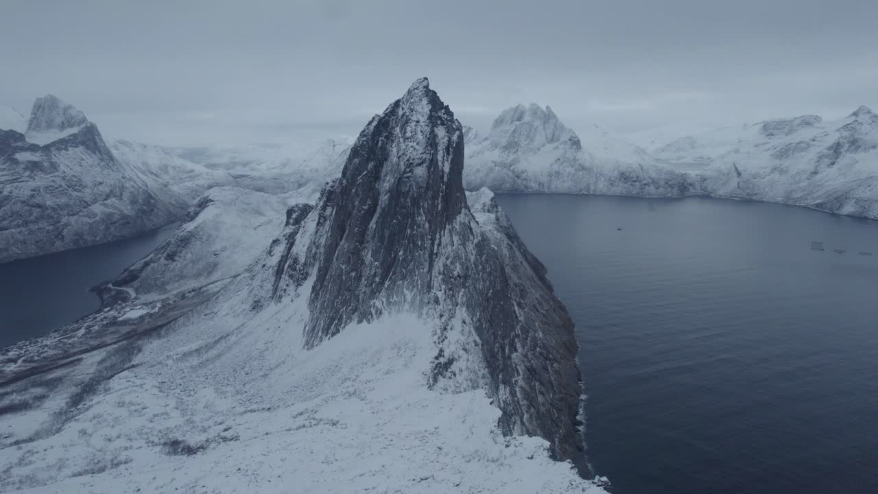 Drohnenaufnahme, die sich dem verschneiten Berg Segla nähert, blaue Stunde in Senja, Norwegen