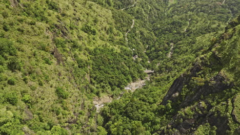 Ella-Sri-Lanka-Aerial-v42-birds-eye-view-drone-flyover-and-around-Ravana-Waterfall-capturing-landscape-of-cliffside-jungle,-verdant-valleys-and-rocky-cliff-walls---Shot-with-Mavic-3-Cine---April-2023