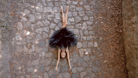 bonita y sensual bailarina de ballet tendida en un suelo pavimentado estirando su cuerpo