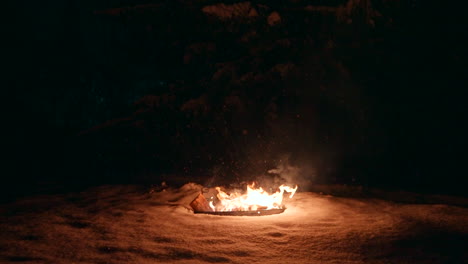 leña quemándose en la nieve por la noche en invierno.