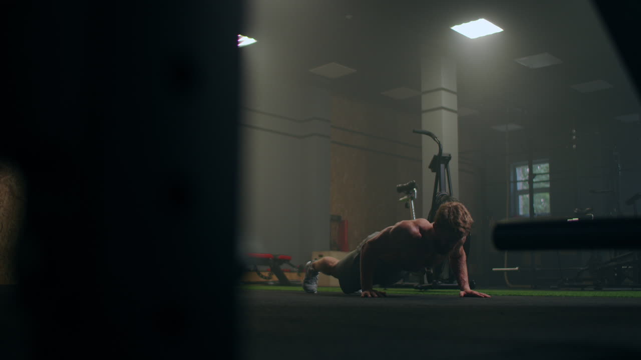 un hombre fuerte realiza flexiones desde el suelo con toda su fuerza. un hombre inflado hace flexiones en el gimnasio