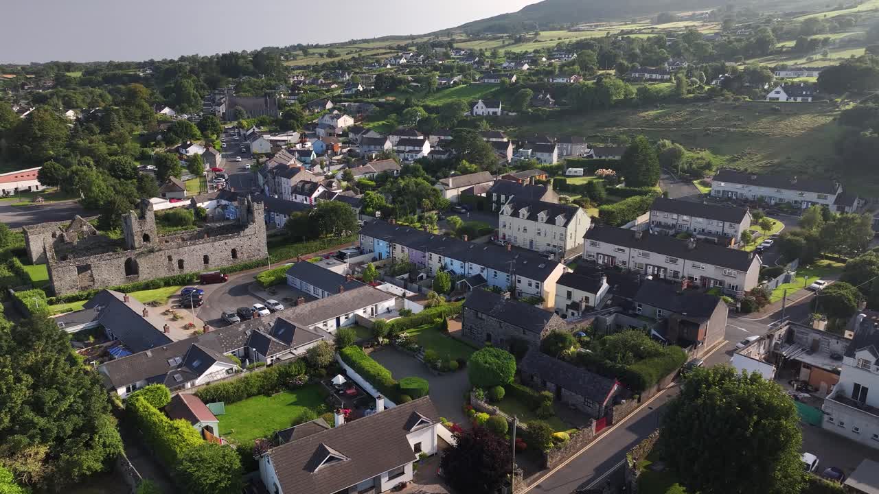Scenic view of street in Carlingford with homes and old Monastery, warm evening light. Ireland