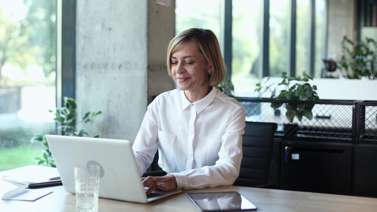 Una donna d'affari sorridente che lavora al portatile in un ufficio moderno