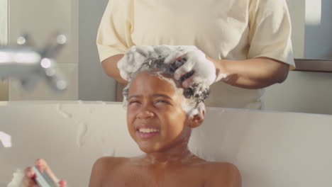 african american woman washing little son in bathroom