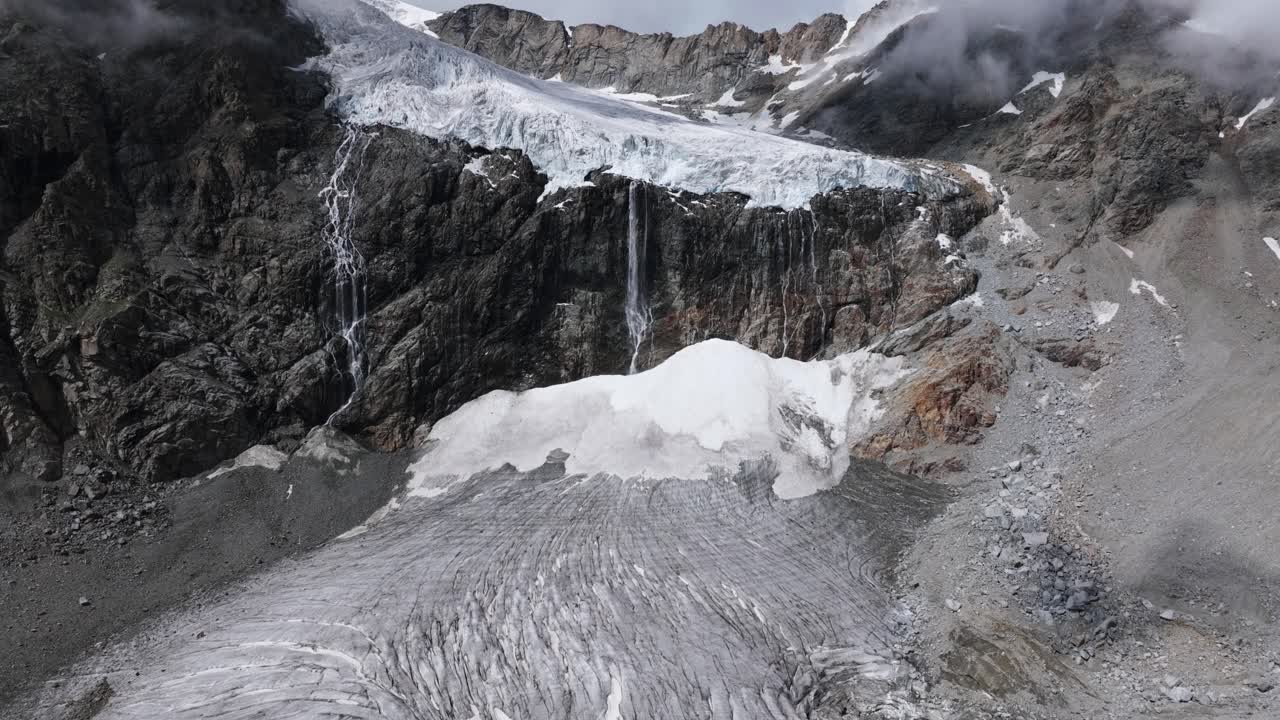 배경 에 폭포 와 바위 산 들 이 있는 펠라리아 빙하 의 영화적 인 모습, 이탈리아 의 발말렌코