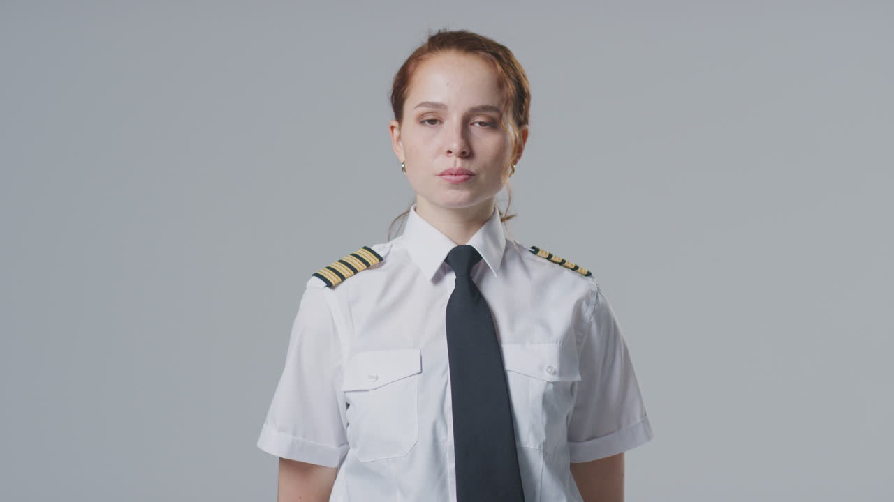 Studio-Porträt einer Pilotin oder Schiffskapitänin vor schlichtem Hintergrund.