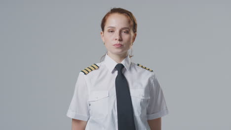 retrato de estudio de una mujer piloto de línea aérea o capitán de barco contra un fondo plano