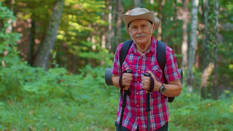 Senior-elderly-tourist-grandfather-training-Nordic-walking-with-ski-trekking-poles,-hiking-in-wood