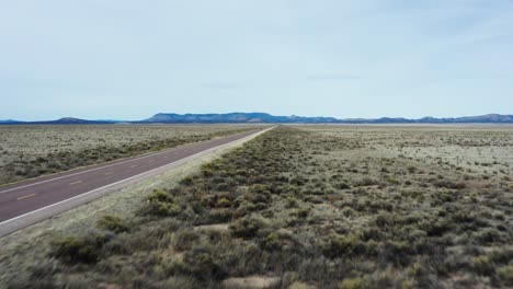 low altitude ascend drone reveal desert highway and single car driving