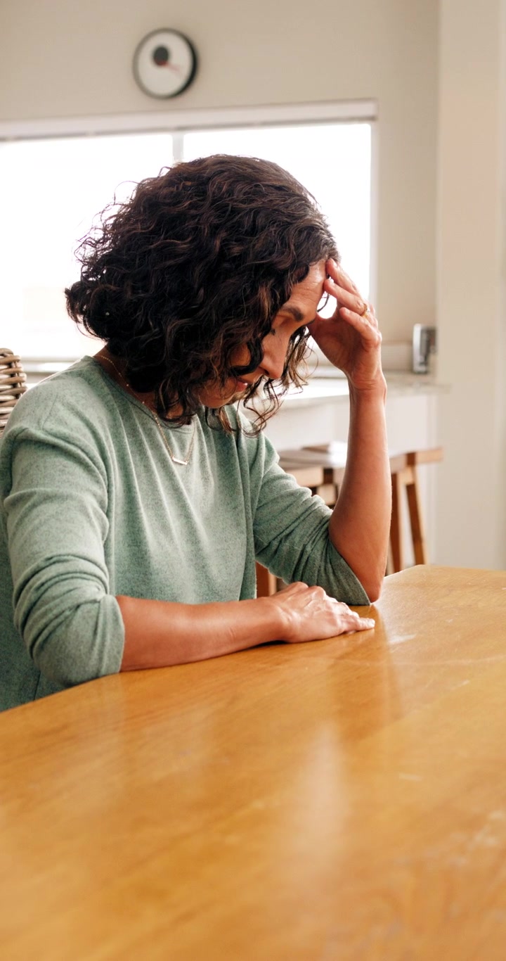 Stressed Woman Sitting at a Table in a Bright Home Interior
