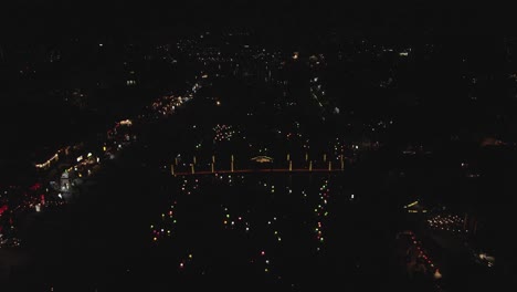 antena de la ciudad del río de la noche oscura: las luces de colores se mueven muy por debajo, patrón
