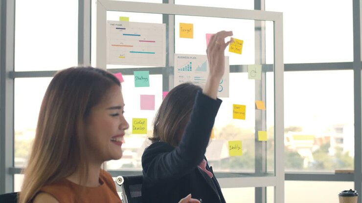 Two businesswoman throwing documents and happy celebrating success at their working places in the modern office, a business having fun together enjoy.