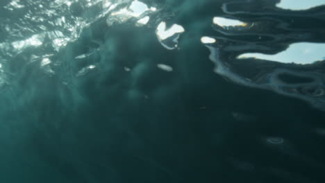 Slow motion barrel seen from below with vortex swirl and glowing light through wave face
