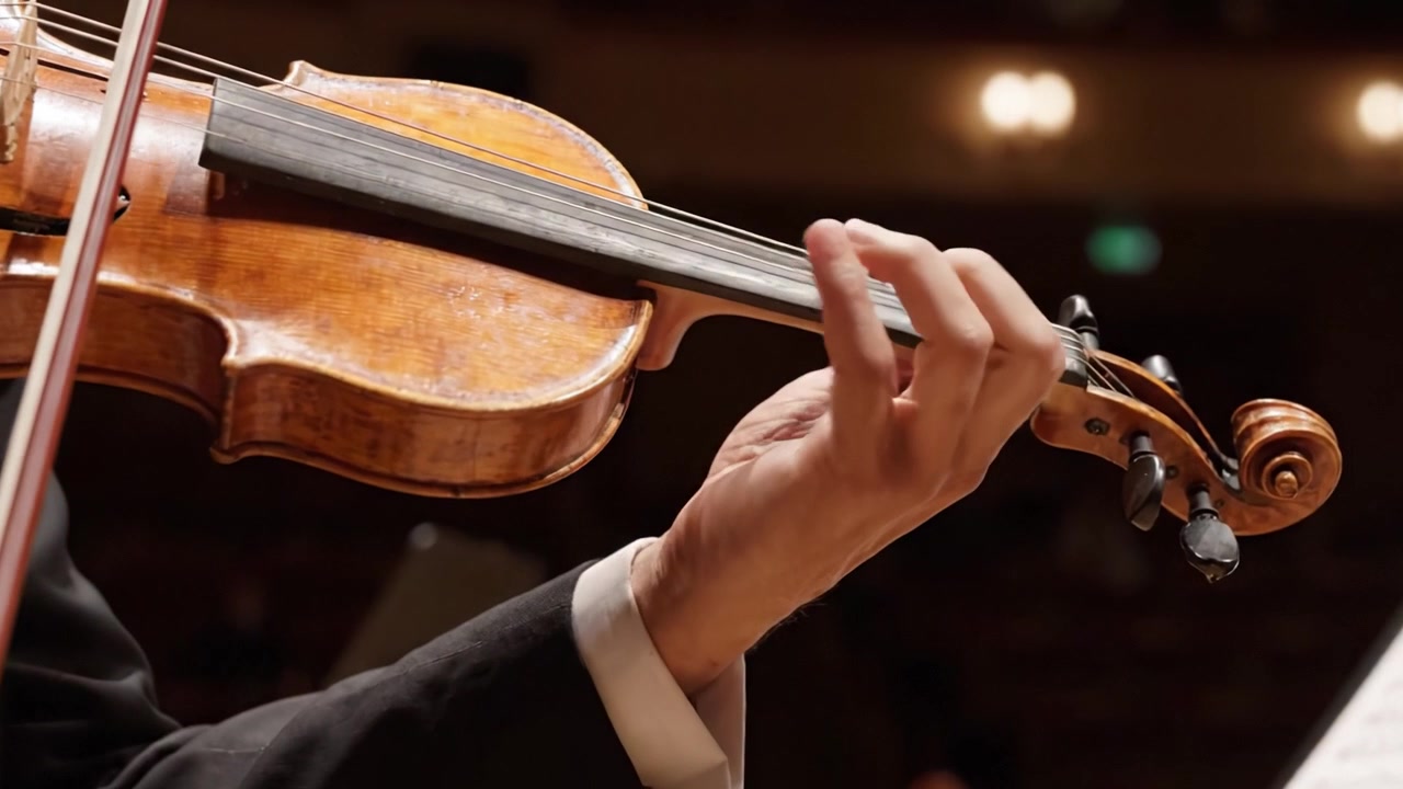 Un primo piano di un'elegante esibizione di violino: catturando l'arte e la precisione della mano di un musicista mentre suona abilmente lo strumento a corda in un'ambientazione incantevole.
