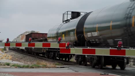 train running on level crossing with low barriers and red lights flashing in fort worth texas, usa